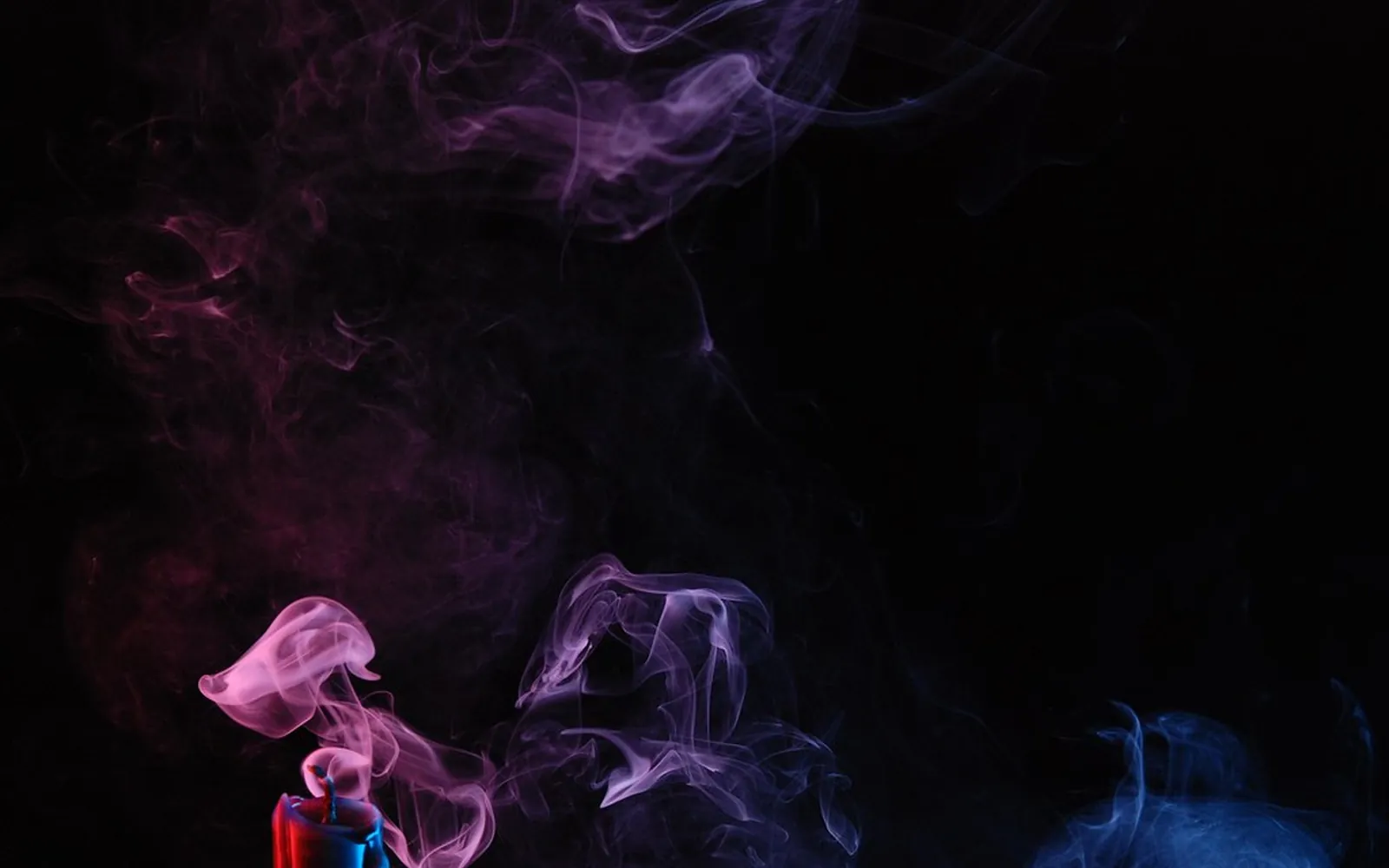Thin trail of smoke rising from a candle against a dark background