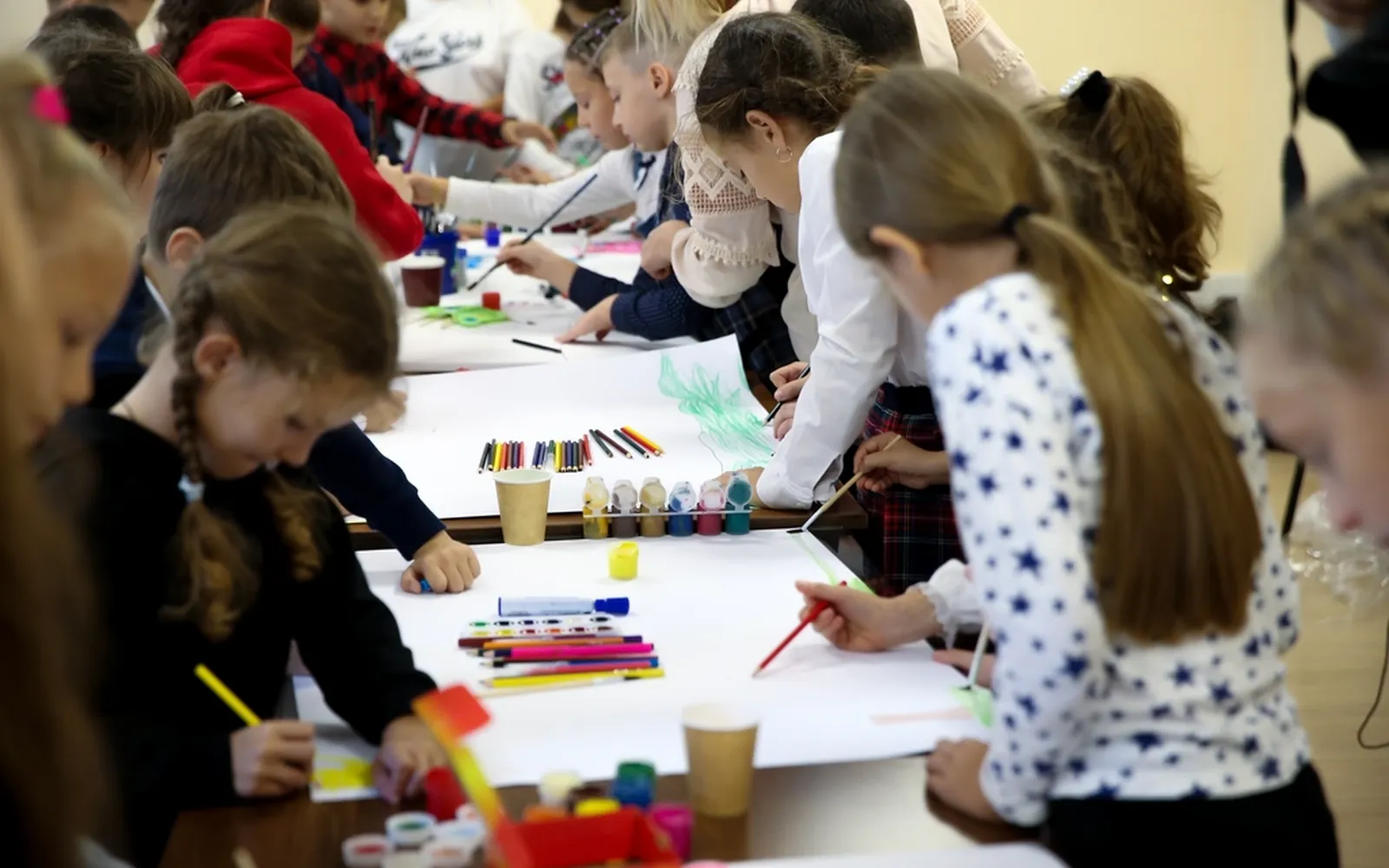 Children painting at tables in an art class