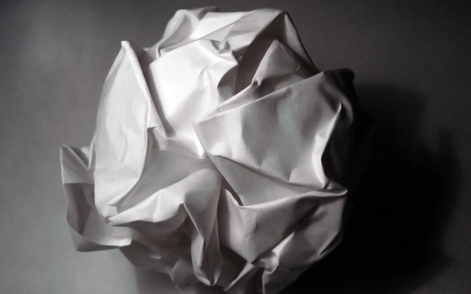 Crumpled ball of thin material on a plain surface, its folds catching the light