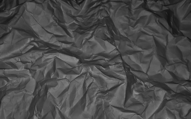 Dark sheet of crumpled paper with a dense network of creases