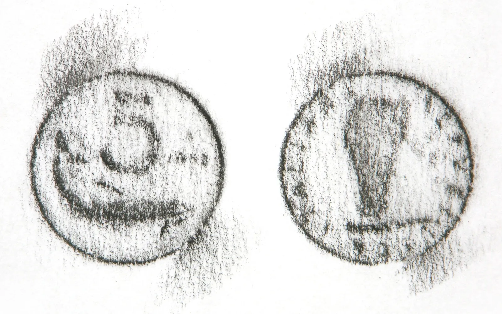 Pencil frottage of two coins on white paper, showing the raised design transferred by rubbing