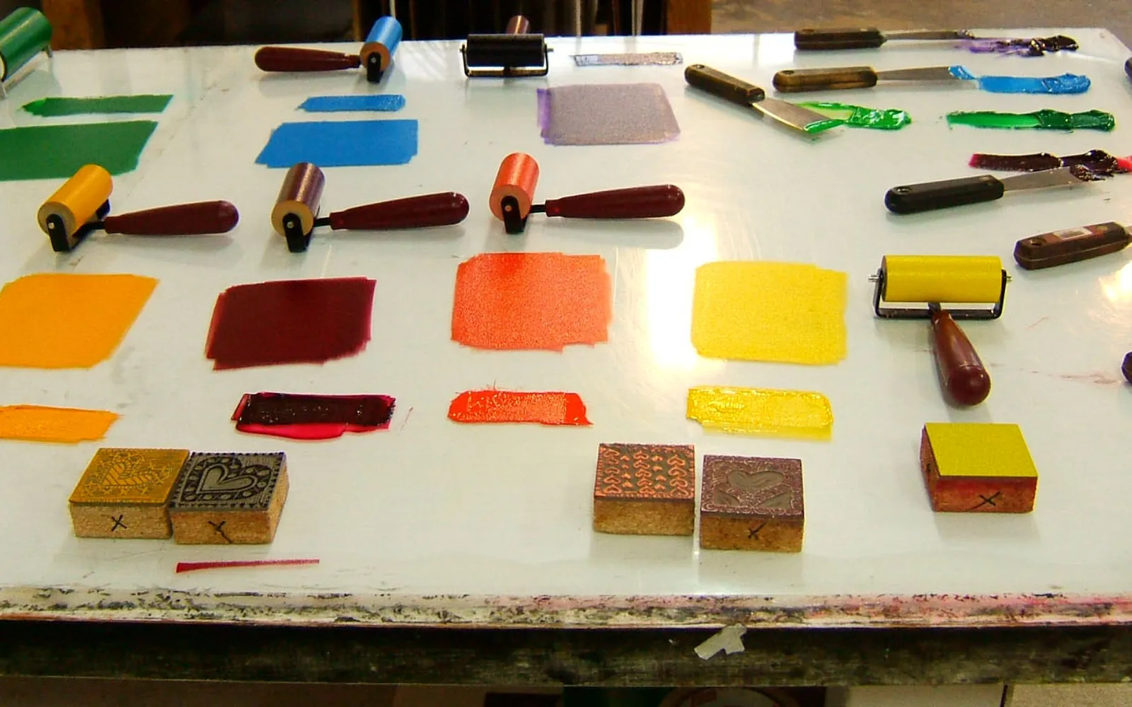 Printmaking rollers and inked surfaces on a workshop table