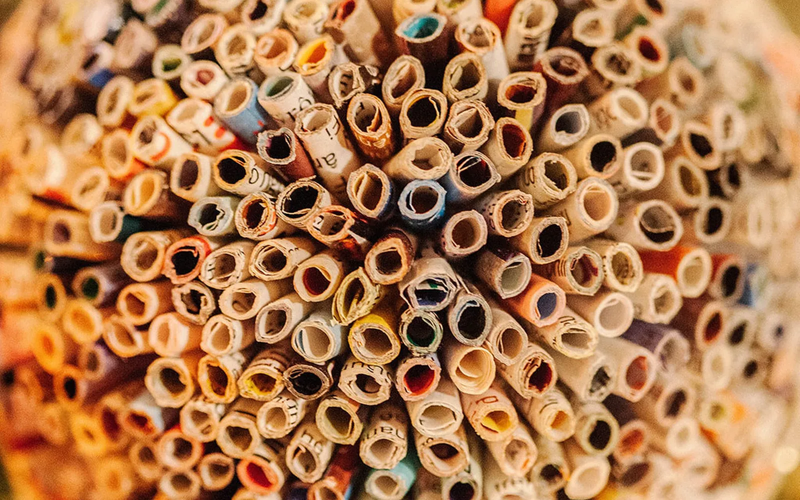 Close-up of a round Christmas ornament made from hundreds of tightly rolled strips of printed recycled paper